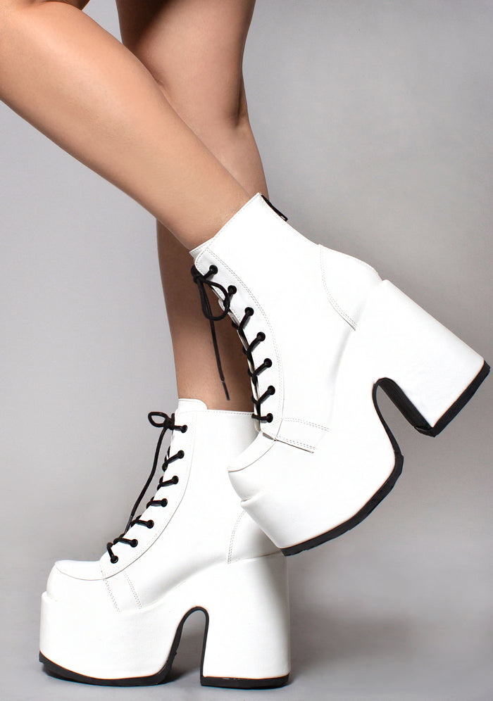 Demonia CAMEL 203 Deja Vu White Platform Boots in white vegan patent leather with chunky grip sole and black lace-up worn by model — side view