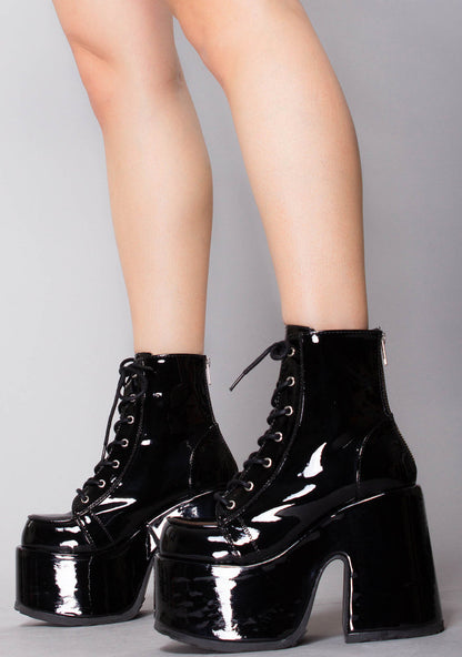 Demonia CAMEL 203 Raise Hell Patent Black Platform Boots in black patent vegan leather with silver metal hardware worn by model — side view 2