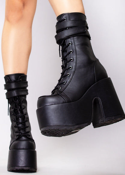 Demonia CAMEL 250 Night Dive Black Platform Boots in black vegan leather with strap buckle front and silver hardware worn by model — side view