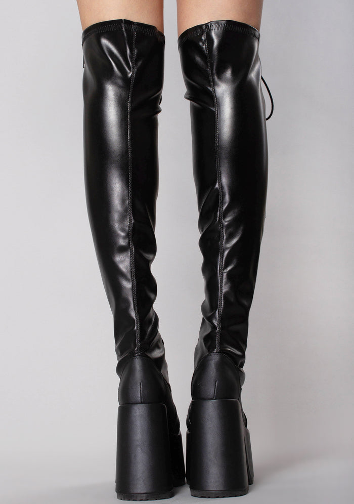 Demonia CAMEL 300 Rude Awakening Thigh-High Black Platform Boots in black vegan leather with full length metal zip closure worn by model — back view