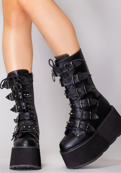 Demonia DAMNED 225 Dark Soul Black Platform Boots in black vegan leather with cone studded buckle straps worn by model — front view