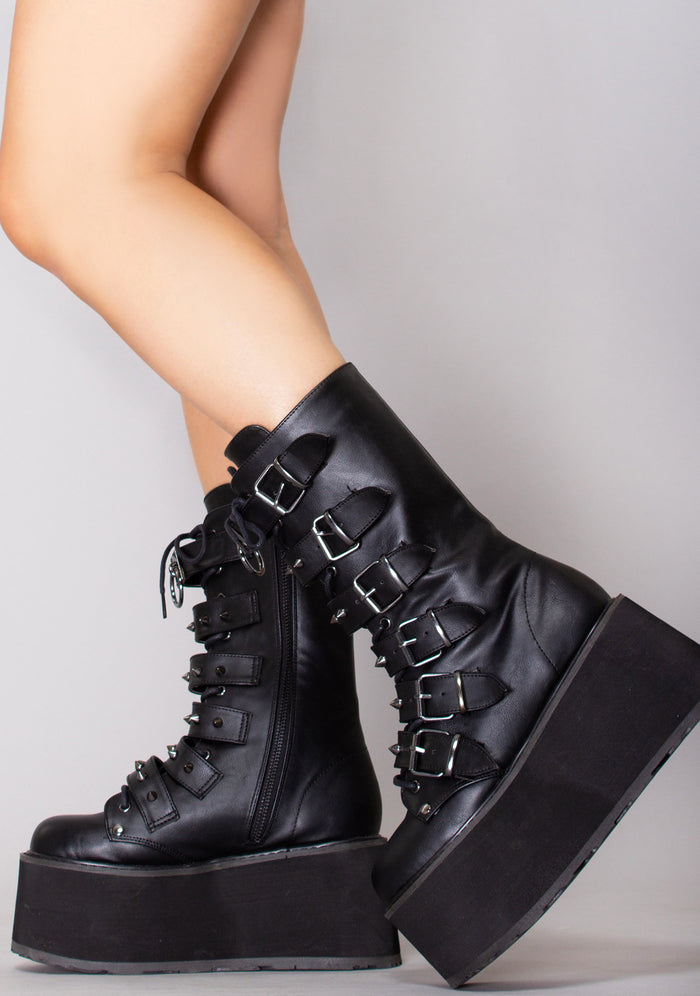 Demonia DAMNED 225 Dark Soul Black Platform Boots in black vegan leather with 6 buckle straps and lace-up front worn by model — side view