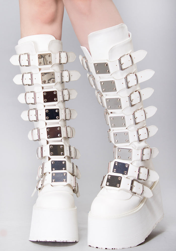 Demonia DAMNED 318 51/50 White Platform Boots in white vegan PU leather with 8 buckle straps and metal plate detail worn by model — front view