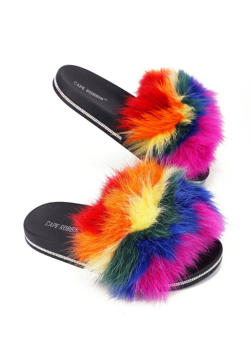 Cape Robbin Fever Dream Faux Fur Sandals featuring a vibrant multicolored rainbow faux fur strap and a black flat slip-on sole wrapped in sparkling rhinestones.