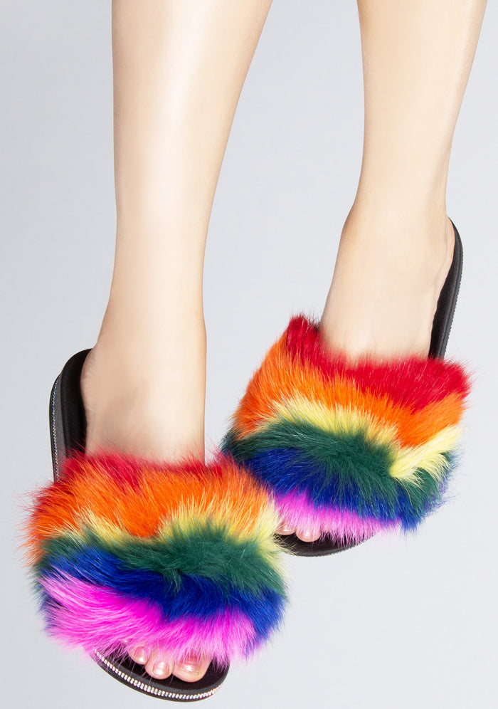 Front view of the multicolored Fever Dream faux fur sandals on-model, showcasing the fluffy rainbow strap and shimmering rhinestone edge details.
