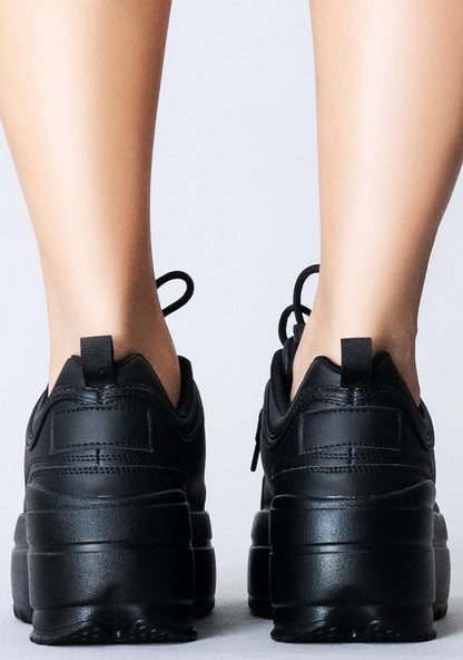 Close-up rear shot of the chunky 2-inch black platform outsoles on-model, emphasizing the rugged texture built for festival dance floors.