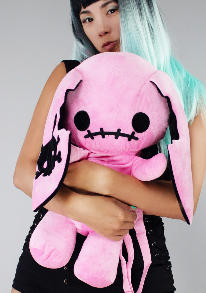 Sleepyville Critters Naughty Bunny Pink Plush Backpack in pink with 3D bunny plush design and skull patch ear accent on kawaii goth rave backpack — model front view