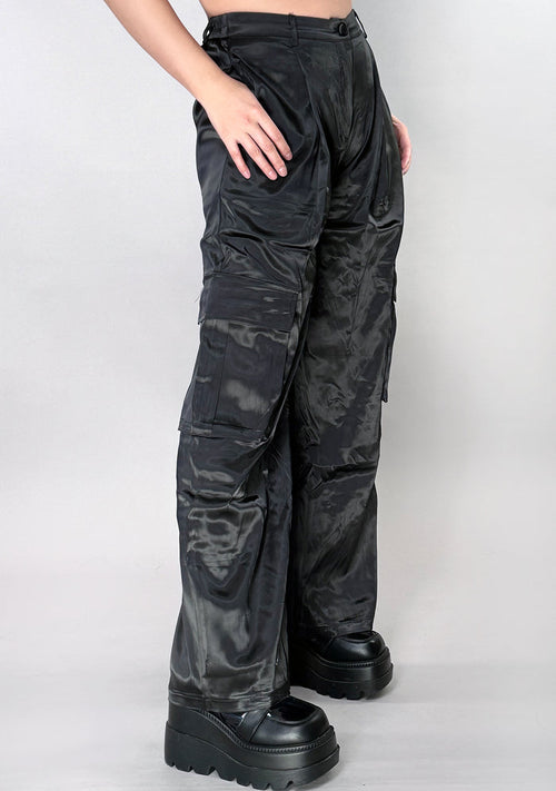 Hot & Delicious Night Beat Black Satin Cargo Pants in black with cargo pockets and button zipper closure on rave bottoms — model view