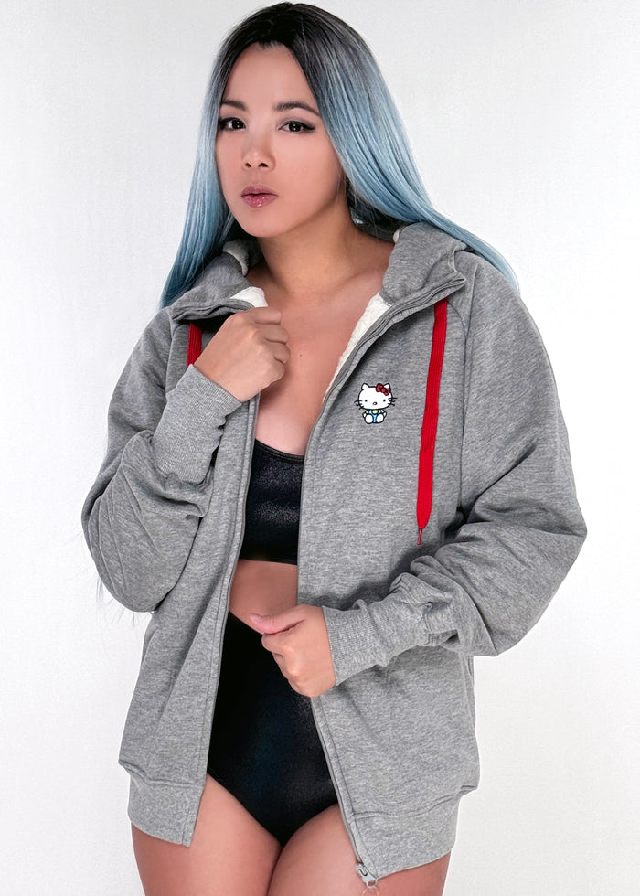 Sanrio Hello Kitty Sherpa Zip Up Hoodie in grey with Hello Kitty embroidery on sherpa-lined zip-up rave festival jacket — model front view