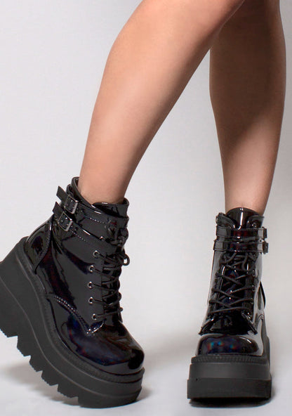 Demonia SHAKER 52 Hologram Black Platform Boots in iridescent holographic vegan leather with lace-up closure and double ankle strap worn by model — front view