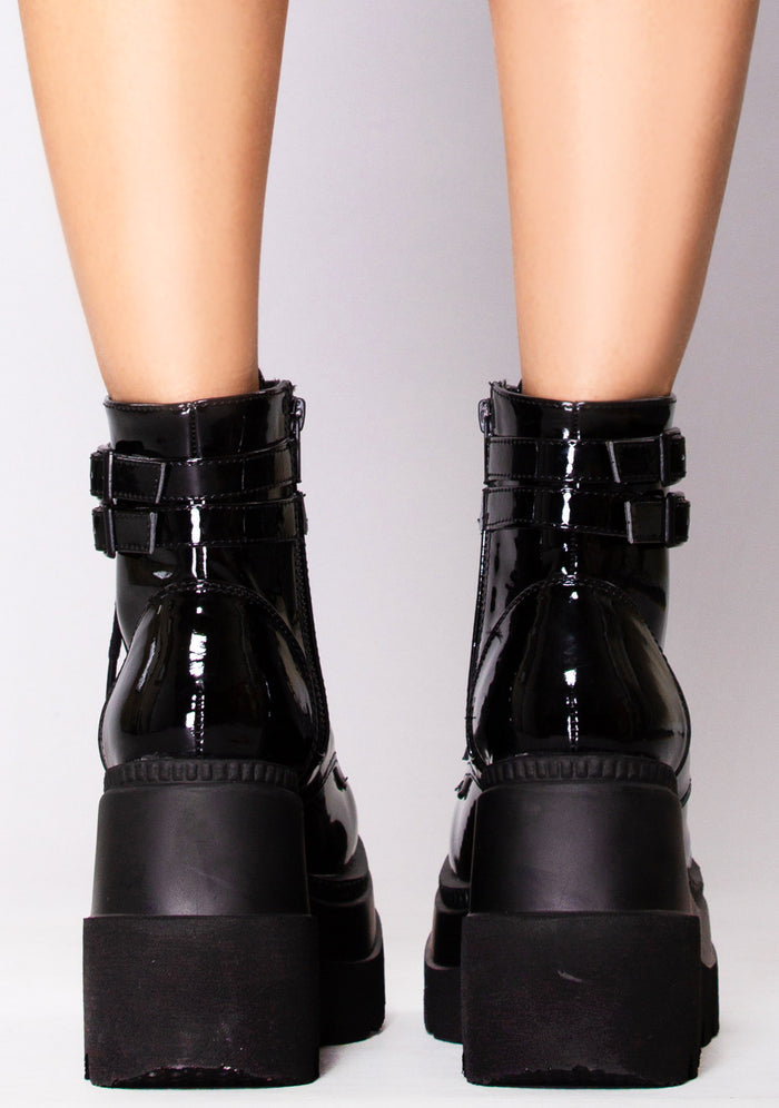 Demonia SHAKER 52 Paint it Black Patent Black Platform Boots in black patent leather with inside zipper closure worn by model — back view