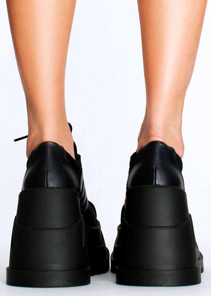 Demonia STOMP 08 Black Rave Platform Sneakers in black vegan leather with chunky rubber wedge platform worn by model — back view