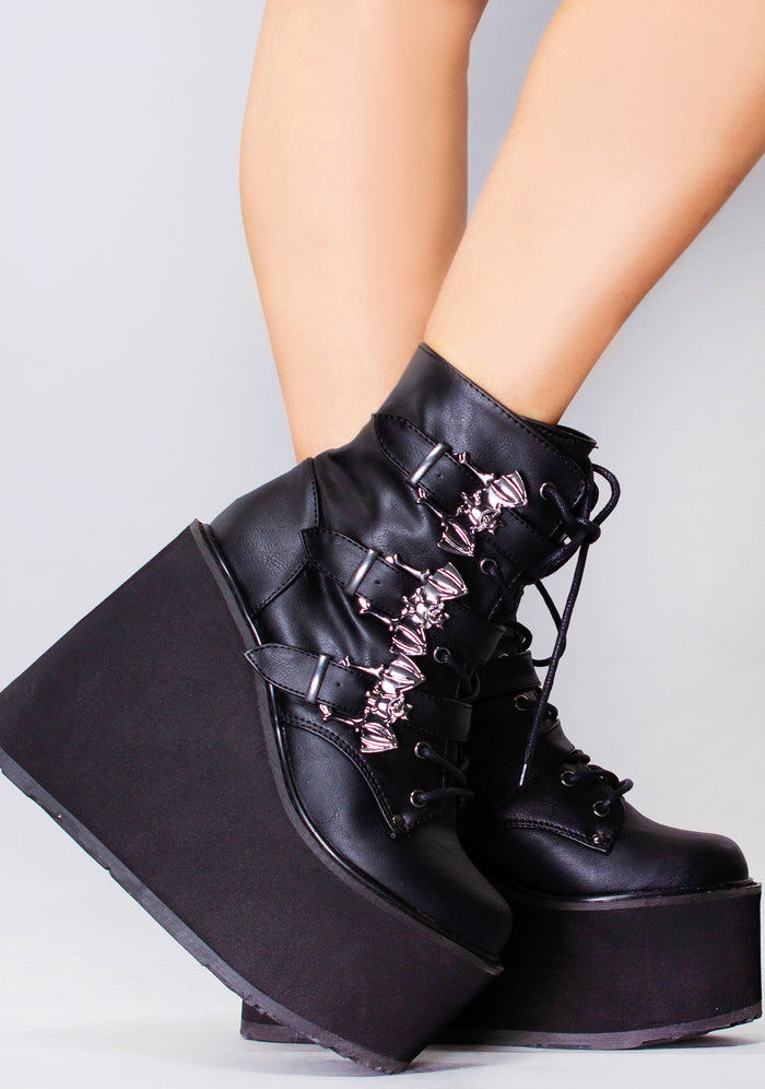 Demonia SWING 103 Creature of the Night Black Platform Boots in black vegan leather with bat buckle straps and lace-up front worn by model — side view