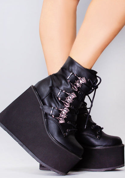 Demonia SWING 103 Creature of the Night Black Platform Boots in black vegan leather with bat buckle straps and lace-up front worn by model — side view