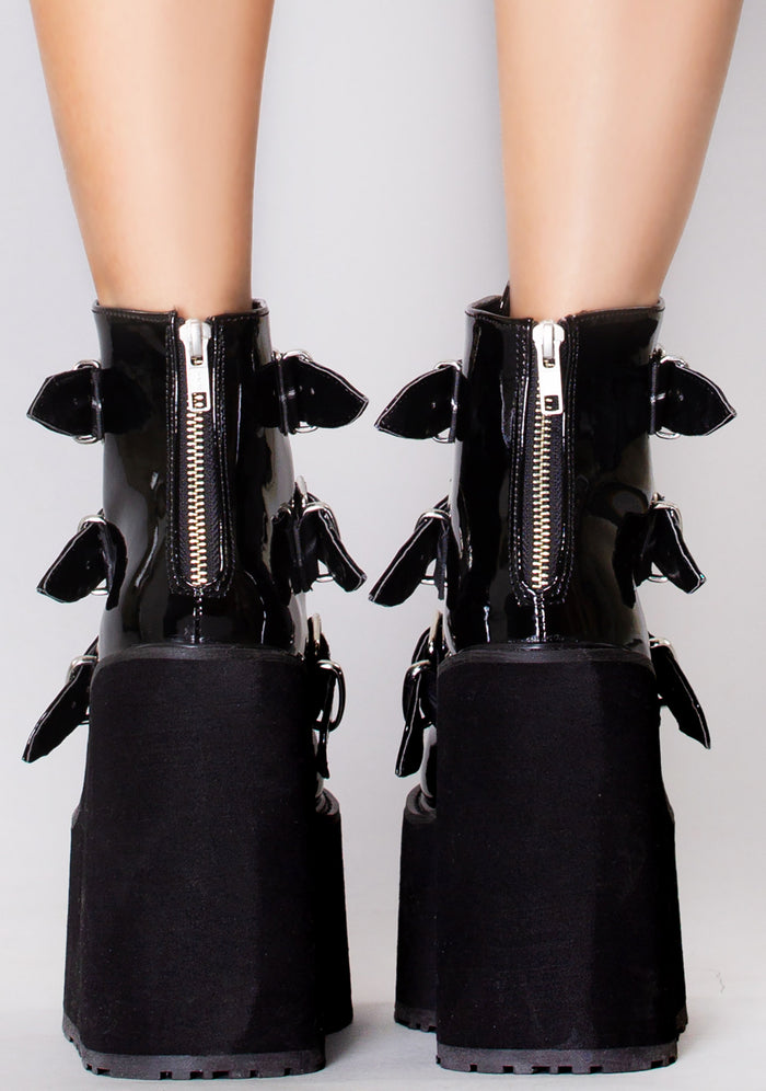 Demonia SWING 105 Dark Resistance Patent Black Platform Boots in black patent leather with back metal zip closure worn by model — back view