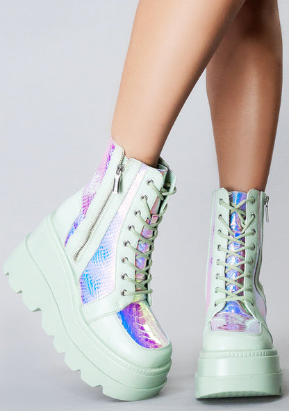 Side angle view of the mint green RADIO rave platform boots on-model, highlighting the contrast of the shimmering iridescent python texture panels under festival lighting.