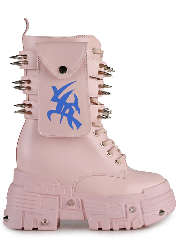 Side studio profile of Anthony Wang X WTF CV Chem Baby Metal Pink platform boots showing the pastel pink faux leather upper, utility side pocket with blue tribal symbol graphic, and spiked chunky platform soles